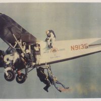 older skydive snohomish plane with seven skydivers hanging on the the outside during flight.