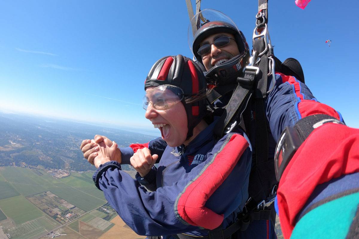 Young female with brown hair smiling and holding hands with tandem instructor.