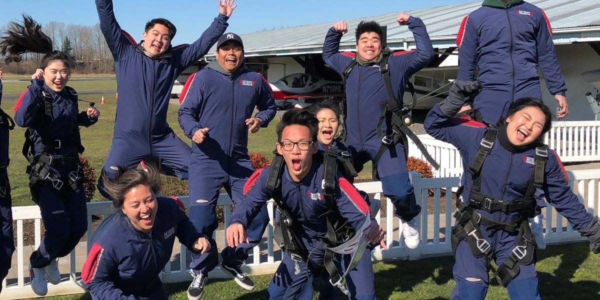 Eleven tandem skydivers jumping in the air excited to go skydiving.