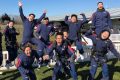 Eleven tandem skydivers jumping in the air excited to go skydiving.