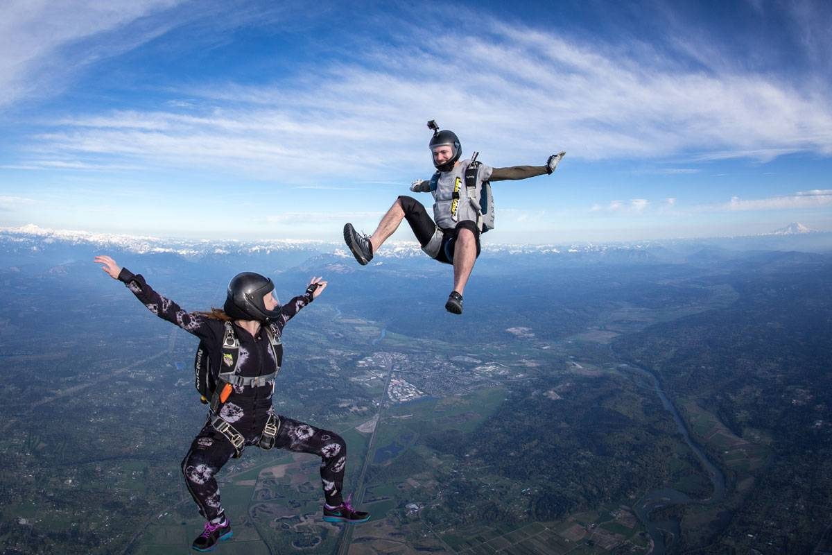 Male and female experienced skydivers in free fall with clear view off the earth below them.