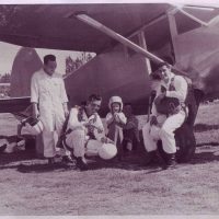 Four gentlemen and child sitting by a plane getting ready to skydive.