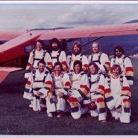 Ten skydivers standing in front of red airplane at Havey Field.