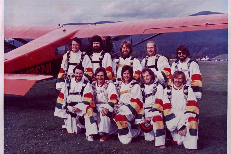 Ten skydivers standing in front of red airplane at Havey Field.