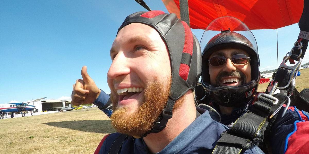 Red headed male tandem student smiling after landing post skydive.