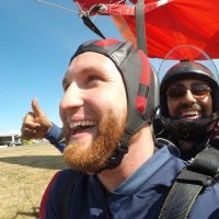 Red headed male tandem student smiling after landing post skydive.