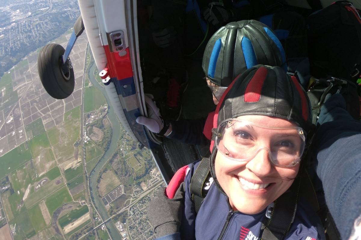 Female tandem skydiver smiling about to take the leap from the airplane.