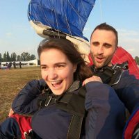 Young female tandem skydiver smiling while landing on the ground with instructor Justin