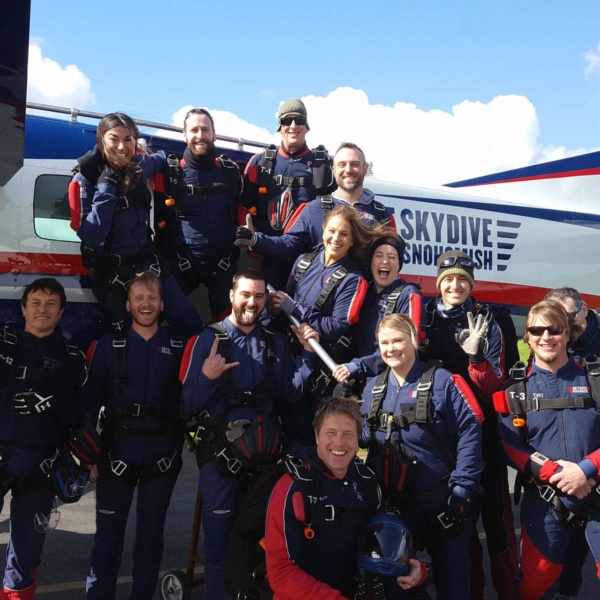 Skydive Snohomish staff smiling in front of Red, White, Blue and Black airplane.