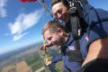 Young male tandem student smiling while skydiving.