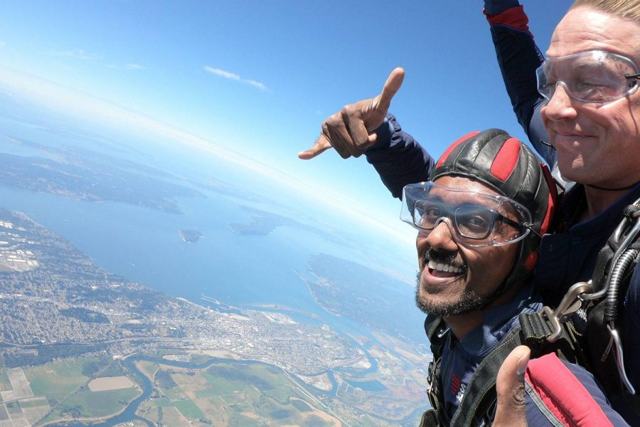 man tandem skydiving gives thumbs up in freefall