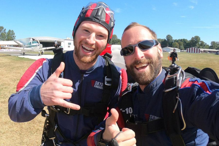 Young male tandem student and instructor giving thumbs up post landing.